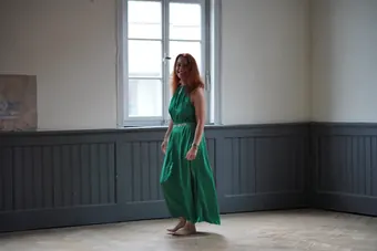Andrea Kirste in a green dress in an empty room