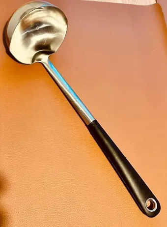 A golden ladle on an orange background