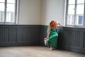 Andrea Kirste in a green dress by the window
